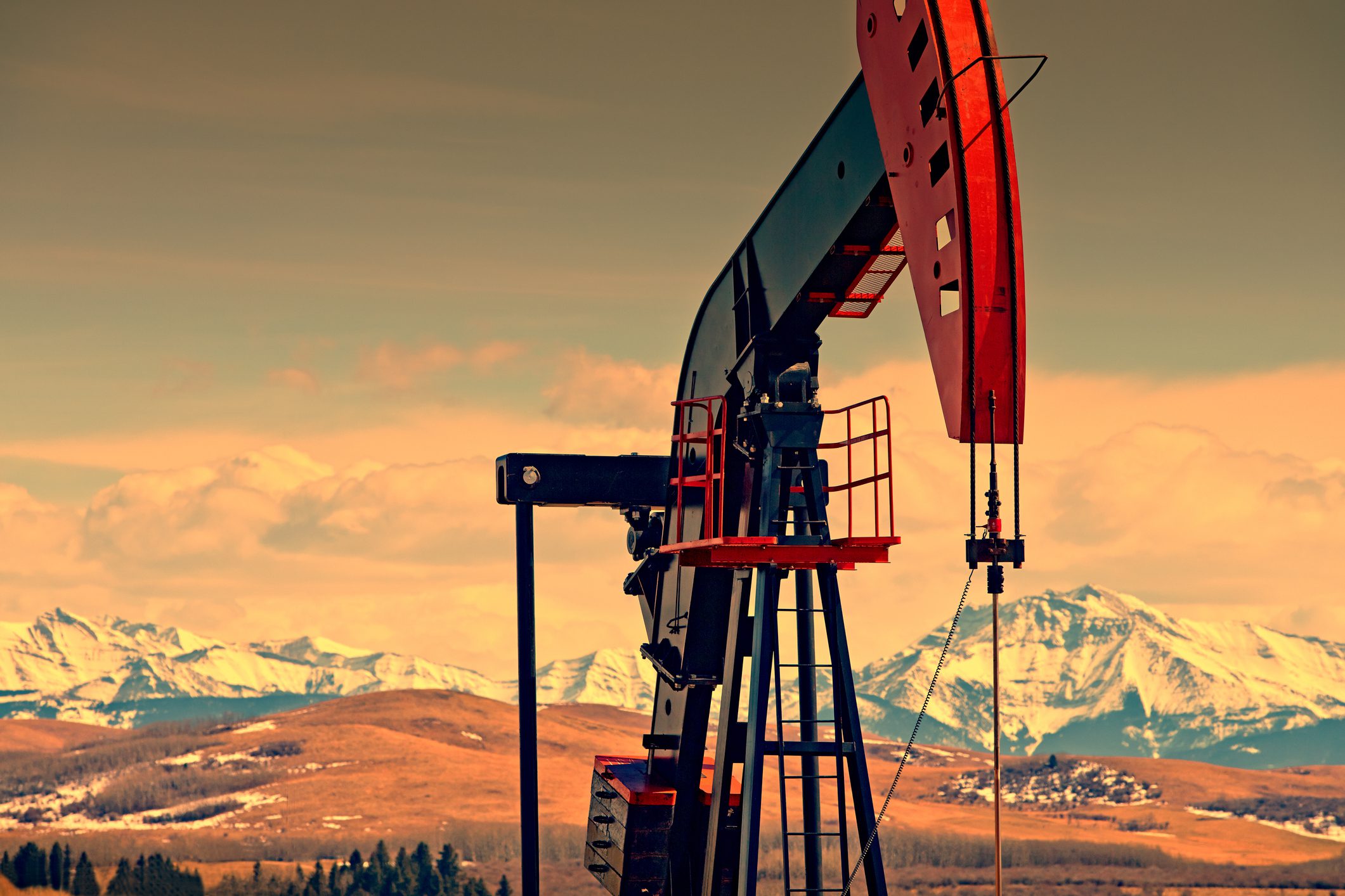 Oil and gas pump jack against mountains, at dusk. Lots of copy space. (Please see my portfolio for related photos and video clips).